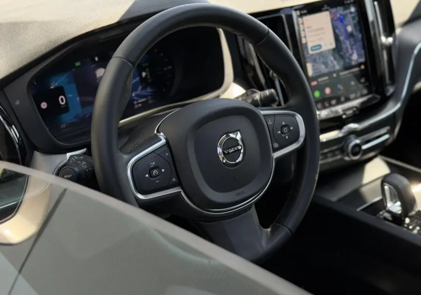 Vue rapprochée du volant noir simili-cuir et du tableau de bord digital du Volvo XC60 2024 T6 AWD PHEV.