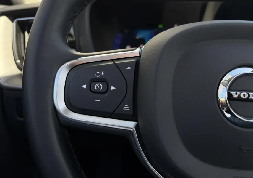 Gros plan sur la partie gauche du volant noir du Volvo XC60 2024 avec commandes de régulateur de vitesse.
