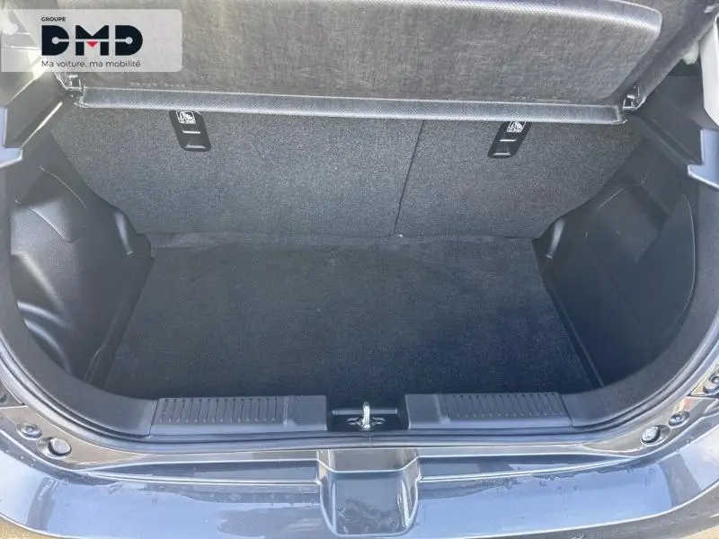 Coffre ouvert vu de l'arrière de la Suzuki Swift 1.2 Hybrid 83ch Privilège 2024 en Mineral Gray Metal, espace de chargement vide.