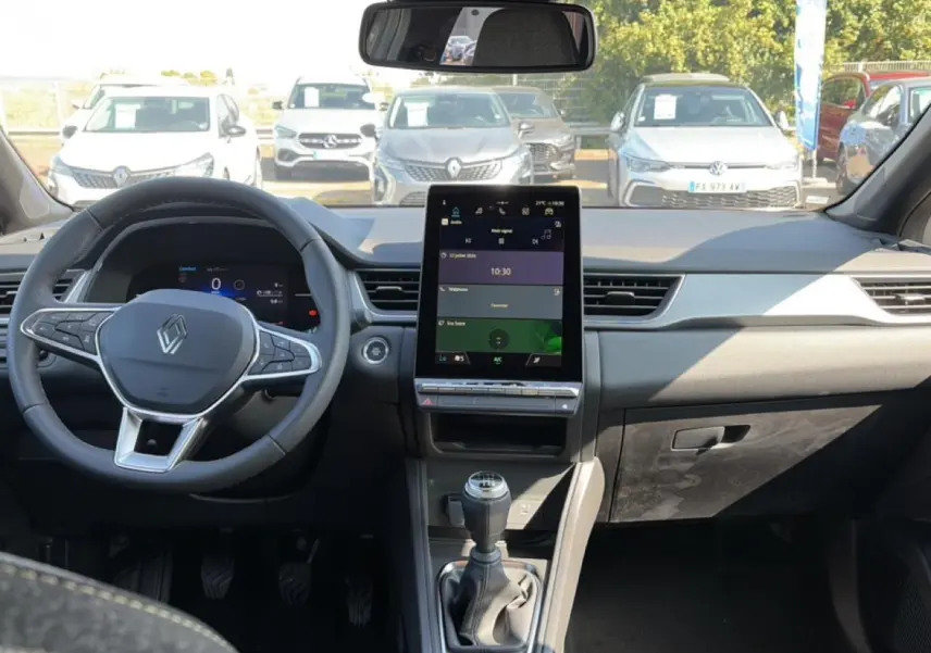 Vue intérieure frontale du Renault Captur 2026 avec tableau de bord noir, écran tactile vertical et levier de vitesse manuel.