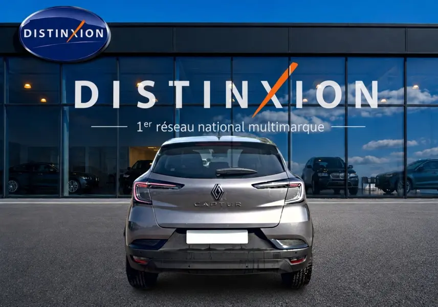 Vue arrière d'un Renault Captur 2026 gris Cassiope avec toit noir, garé devant une vitrine Distinxion.