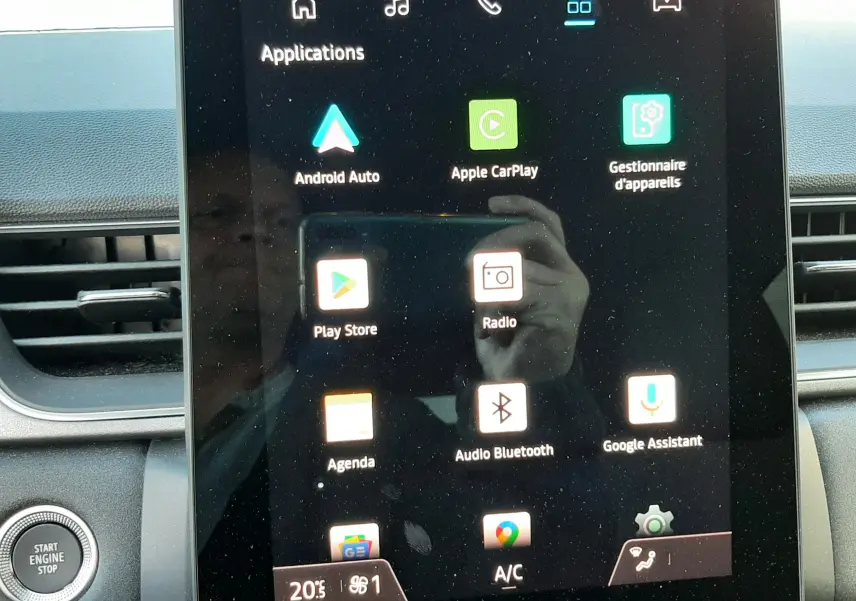 Écran tactile central du Renault Captur 2024 affichant les applications Android Auto, Apple CarPlay et radio, avec bouton start engine stop visible.