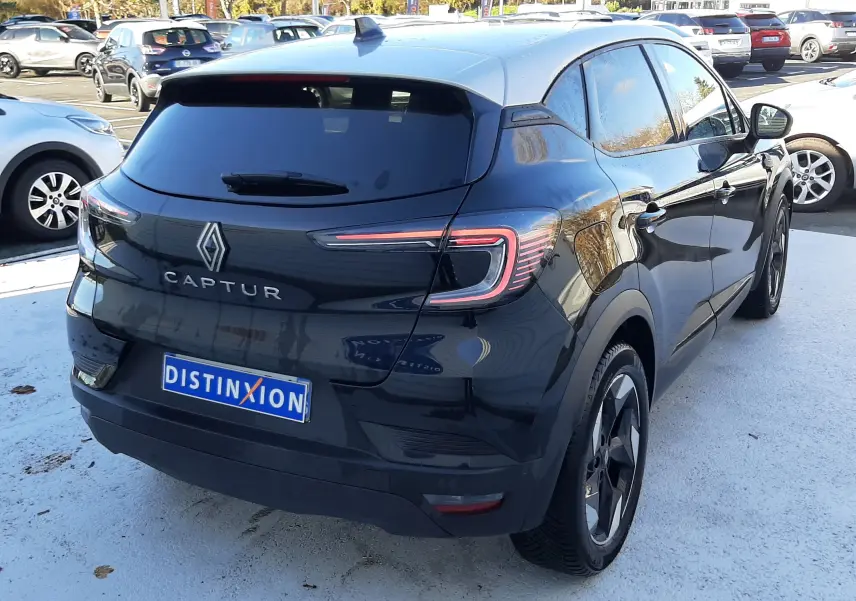 Vue 3/4 arrière droite d'un Renault Captur 2024 noir métal avec toit gris, feux LED et jantes biton visibles.