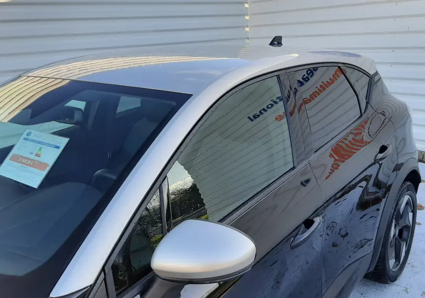 Vue 3/4 avant droit du Renault Captur 2024 noir métal avec toit gris et rétroviseur argenté, vitres teintées.