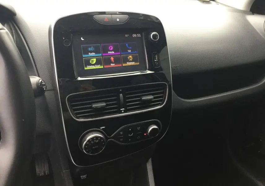 Vue intérieure centrée sur la console centrale noire brillante avec écran tactile et commandes de climatisation d'une Renault Clio IV Estate.