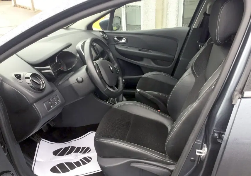 Vue intérieure côté conducteur de la Renault Clio IV Estate gris titanium, montrant les sièges en cuir et le tableau de bord.