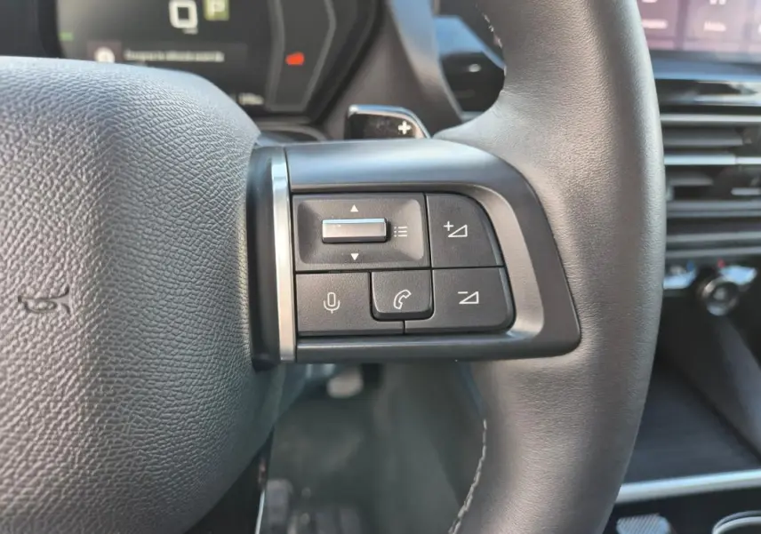Gros plan sur les commandes au volant cuir noir du Citroën C5 X 2024, avec boutons de volume et appel intégrés.