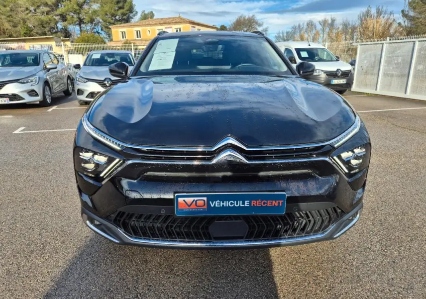 Vue avant d'une Citroën C5 X noire 2024 avec calandre chromée et feux LED fins, stationnée en extérieur.