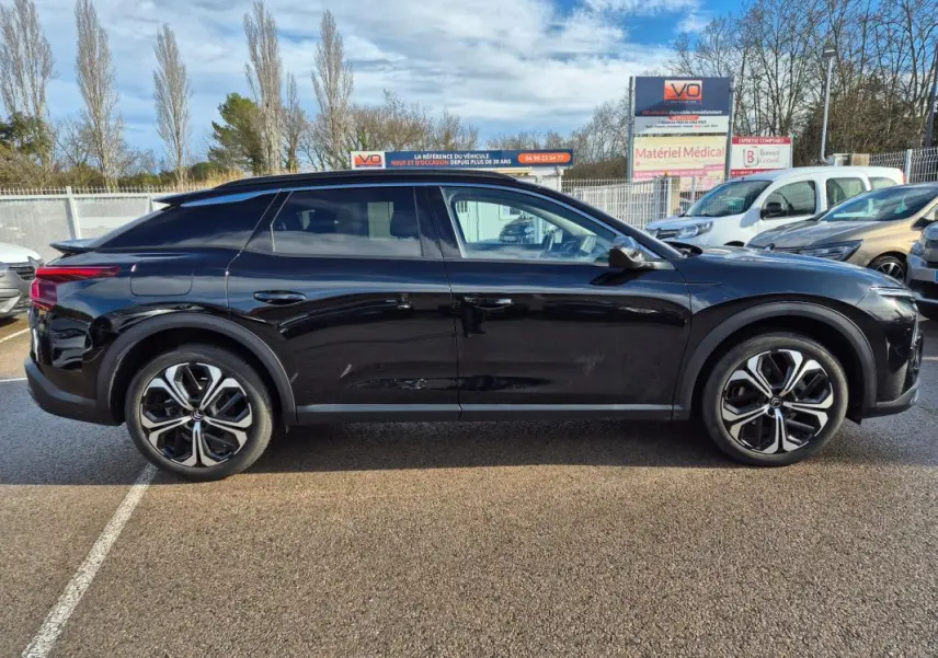 Profil latéral droit d'une Citroën C5 X noire 2024 avec jantes alliage 19 pouces et toit plongeant distinctif.