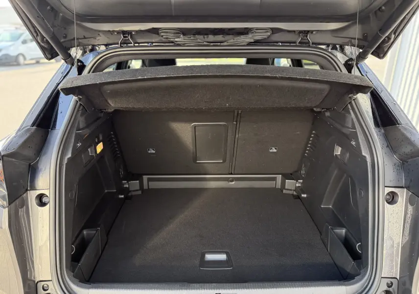 Coffre ouvert vu de l'arrière d'un Peugeot 3008 gris 2022, montrant un espace de chargement propre et bien agencé.
