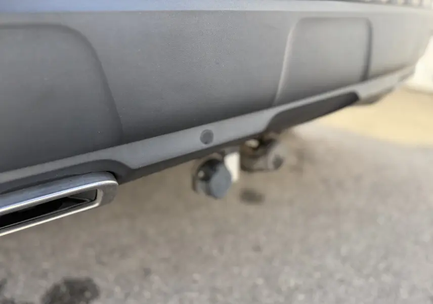 Gros plan sur l'attelage et l'échappement chromé du pare-chocs arrière gris du Peugeot 3008 2022.
