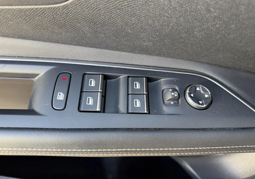 Vue rapprochée des commandes de lève-vitres et réglage des rétroviseurs sur la porte côté gauche d’un Peugeot 3008 gris.