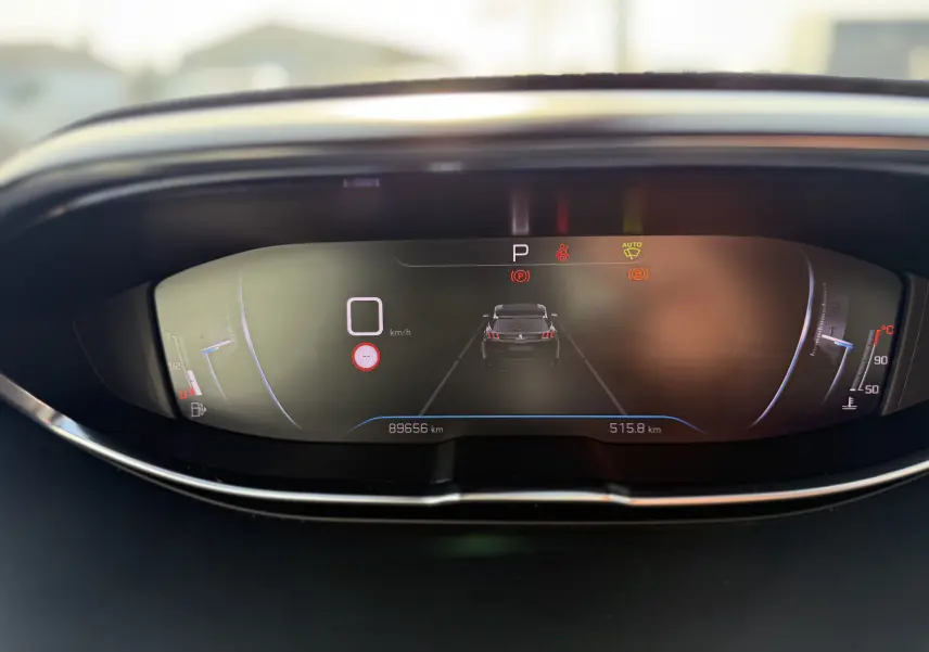 Vue rapprochée du tableau de bord numérique du Peugeot 3008 gris, affichant la vitesse à 0 km/h et divers indicateurs.