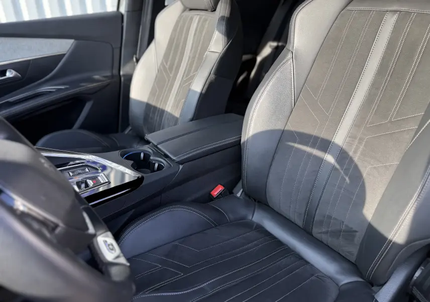 Vue intérieure rapprochée des sièges avant en cuir noir avec surpiqûres blanches du Peugeot 3008 gris 2022.