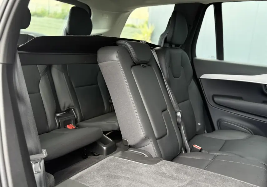 Vue intérieure côté droit des sièges arrière noirs en cuir du Volvo XC90 T8 AWD PHEV 2024 avec troisième rangée rabattue.