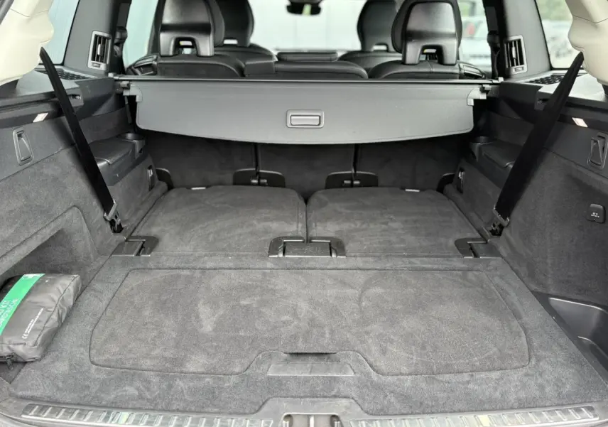 Coffre spacieux du Volvo XC90 gris Dusk, sièges arrière rabattus et cache-bagages déployé, vue arrière intérieure.