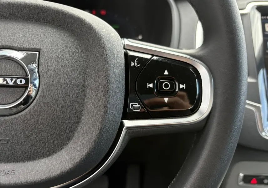 Gros plan sur la partie droite du volant noir du Volvo XC90 2024 avec commandes vocales et multimédia intégrées.