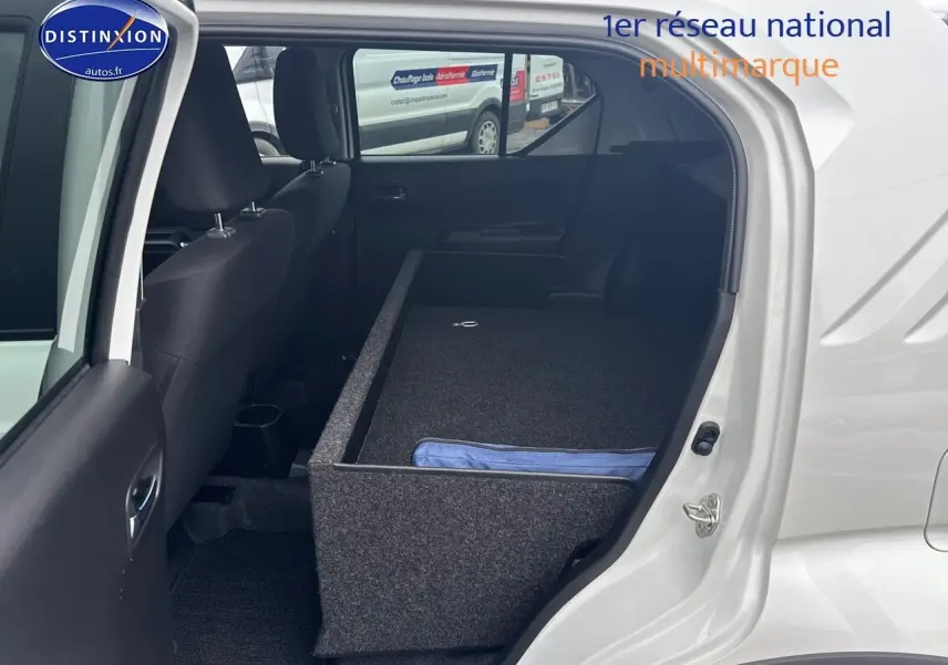 Vue intérieure côté gauche de la Suzuki Ignis blanche 2023 avec banquette arrière rabattue et rangement installé.