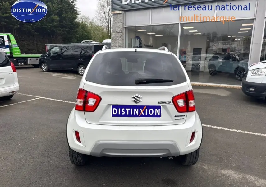 Vue arrière d'une Suzuki Ignis blanche Pure White Pearl métallisé garée devant un showroom Distinxion.