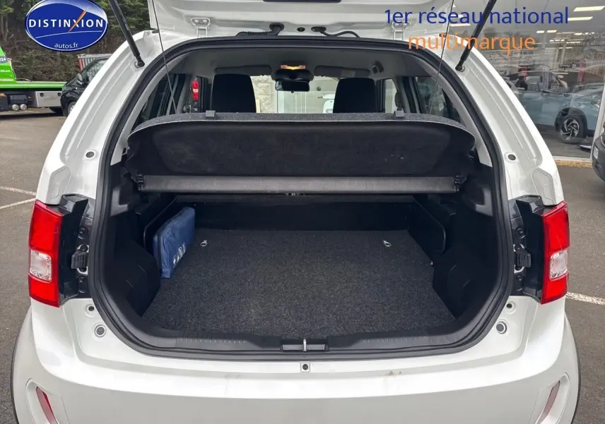 Vue arrière du coffre ouvert d'une Suzuki Ignis 2023 blanche Pure White Pearl métallisé, avec cache-bagages et intérieur noir.