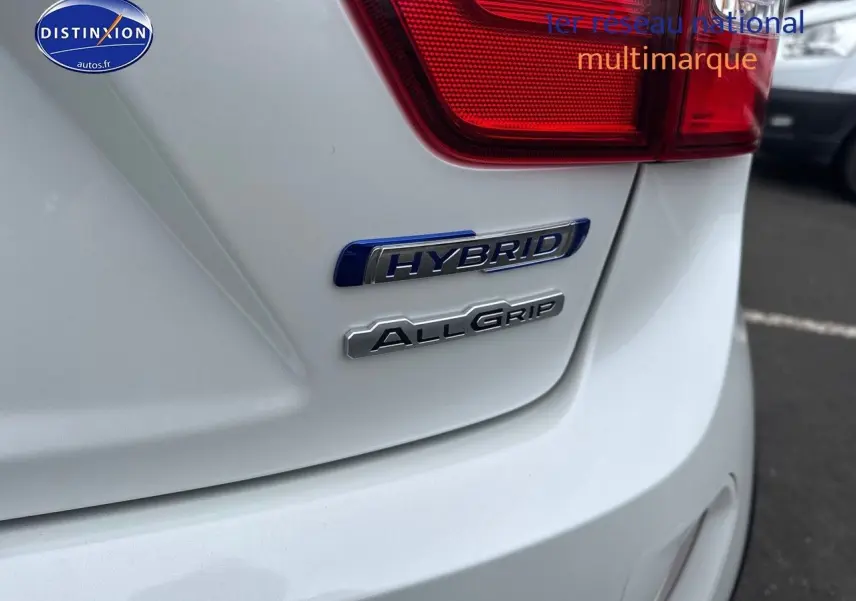 Gros plan sur l'arrière droit blanc nacré d'une Suzuki Ignis 2023 avec badges Hybrid et AllGrip visibles.