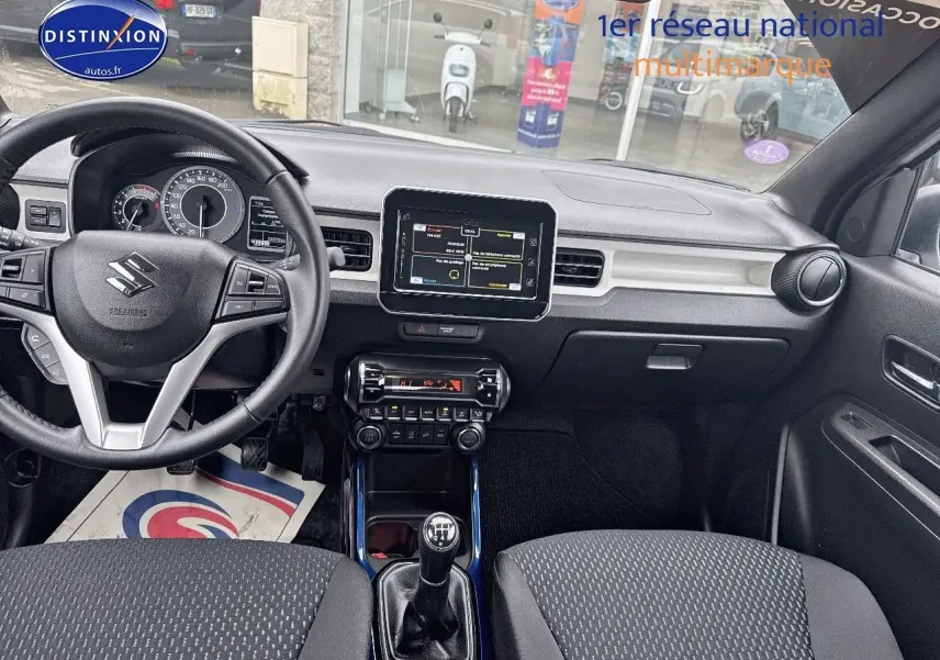 Vue intérieure avant de la Suzuki Ignis 2023 blanche, volant cuir multifonction et écran tactile central visible.