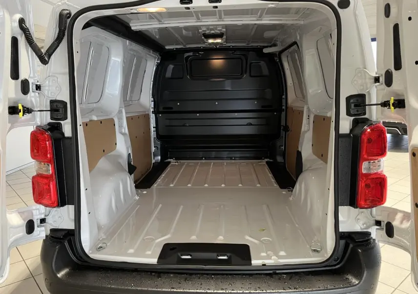 Vue arrière ouverte du Peugeot Expert Fourgon blanc 2024, montrant l'espace de chargement vide avec parois protégées et plancher métallique.