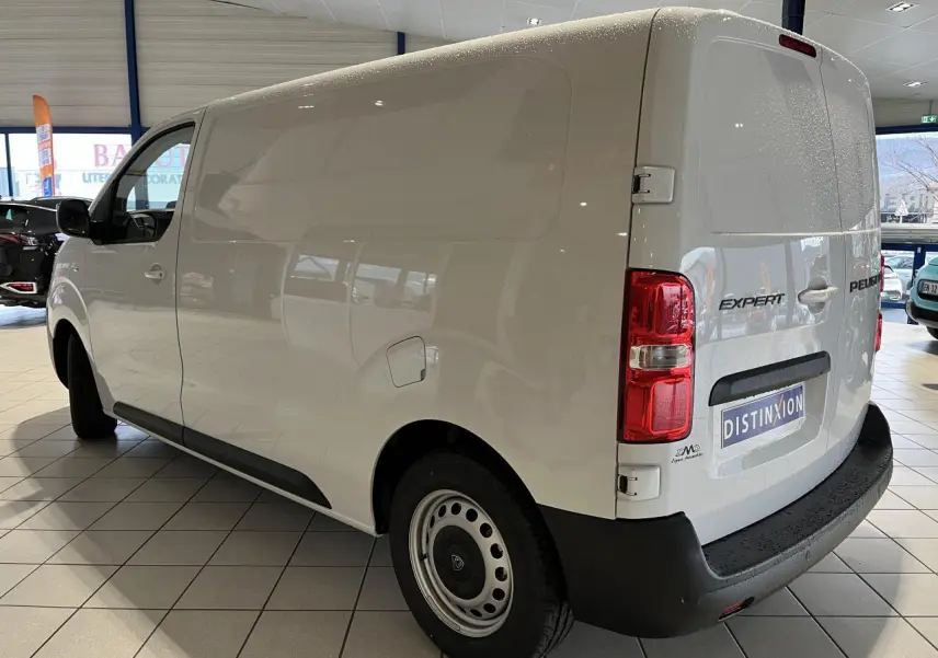 Vue 3/4 arrière droite d’un Peugeot Expert Fourgon blanc 2024 en intérieur, avec feux arrière et pare-chocs noirs visibles.
