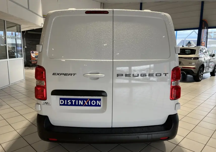 Vue arrière du Peugeot Expert Fourgon blanc 2024 avec portes battantes et feux rouges visibles en intérieur showroom.