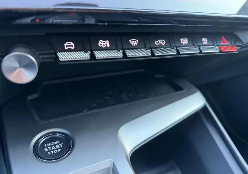 Gros plan sur la console centrale de la Peugeot 308 2024 noire, avec boutons de commande et bouton start/stop visible.