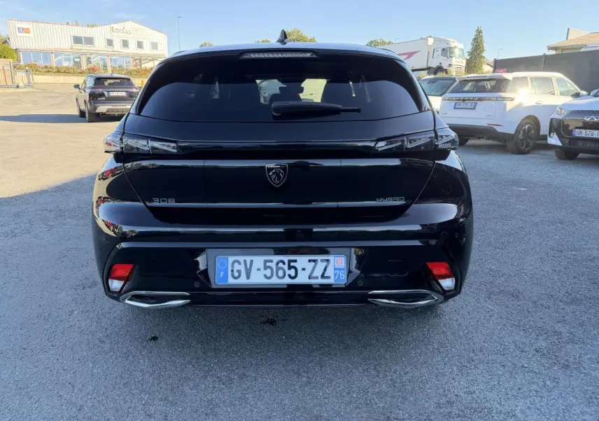 Vue arrière d'une Peugeot 308 noire métallisée 2024 avec feux arrière à signature lumineuse griffe à griffe.