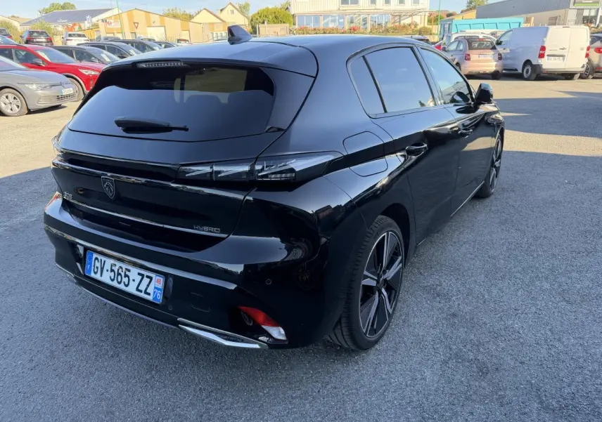 Vue 3/4 arrière droite d'une Peugeot 308 noire métallisée avec feux arrière à signature lumineuse griffe à griffe.
