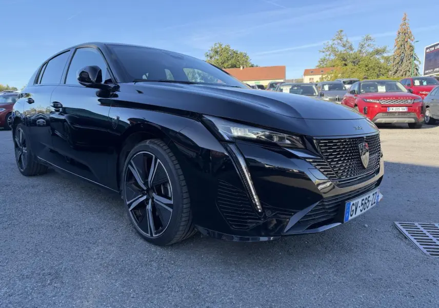 Peugeot 308 noire vue 3/4 avant droit, avec calandre noire vernie et jantes alliage 18 pouces diamantées.