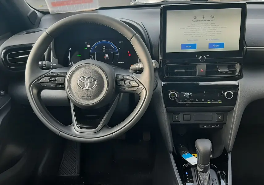 Intérieur de la Toyota Yaris Cross 130H Design 2025, vue frontale du tableau de bord avec écran tactile et volant multifonction.