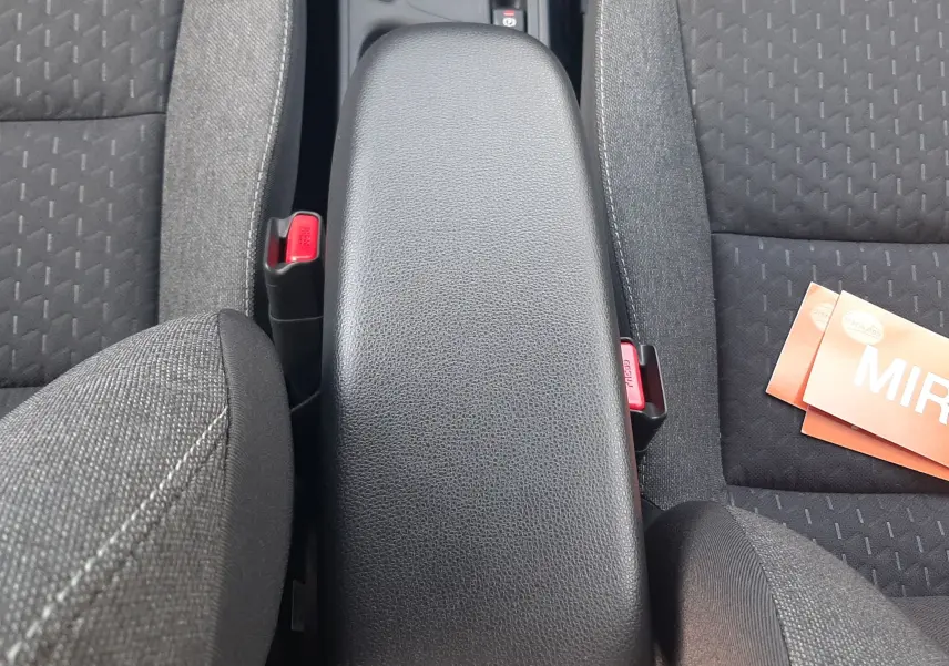Vue plongeante sur l'accoudoir central noir et les sièges en tissu gris foncé de la Toyota Yaris Cross 130H Design 2025.