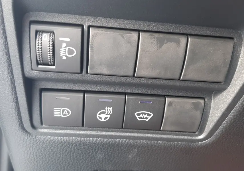Panneau de commandes noires avec réglage des phares, chauffage de volant et dégivrage sur Toyota Yaris Cross 130H gris minéral.