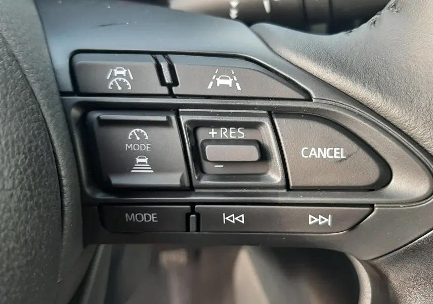 Gros plan sur les commandes au volant du Toyota Yaris Cross 130H Design, boutons de régulateur de vitesse et assistance de maintien de voie.