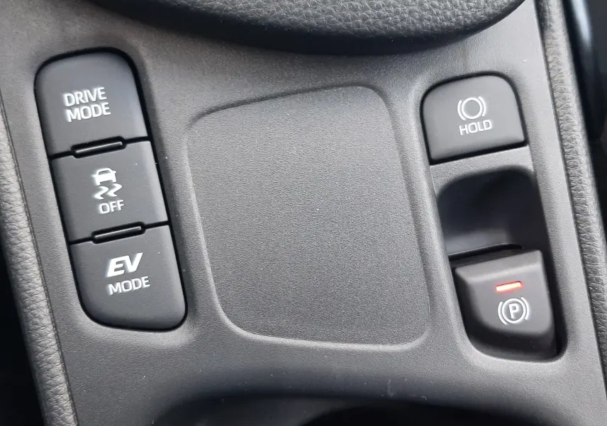 Gros plan sur les commandes centrales noires de la Toyota Yaris Cross 130H Design, avec boutons Drive Mode, EV Mode et frein à main électronique.
