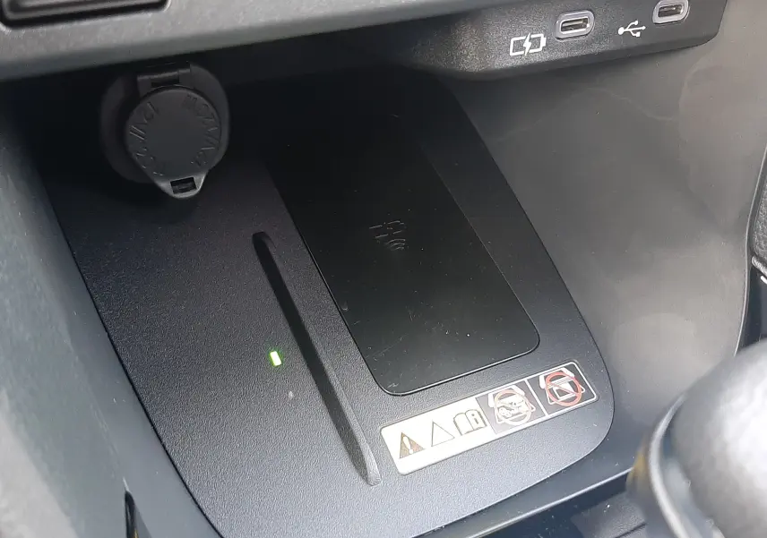 Gros plan sur la zone de recharge sans fil et ports USB dans l'habitacle gris de la Toyota Yaris Cross 130H Design 2025.