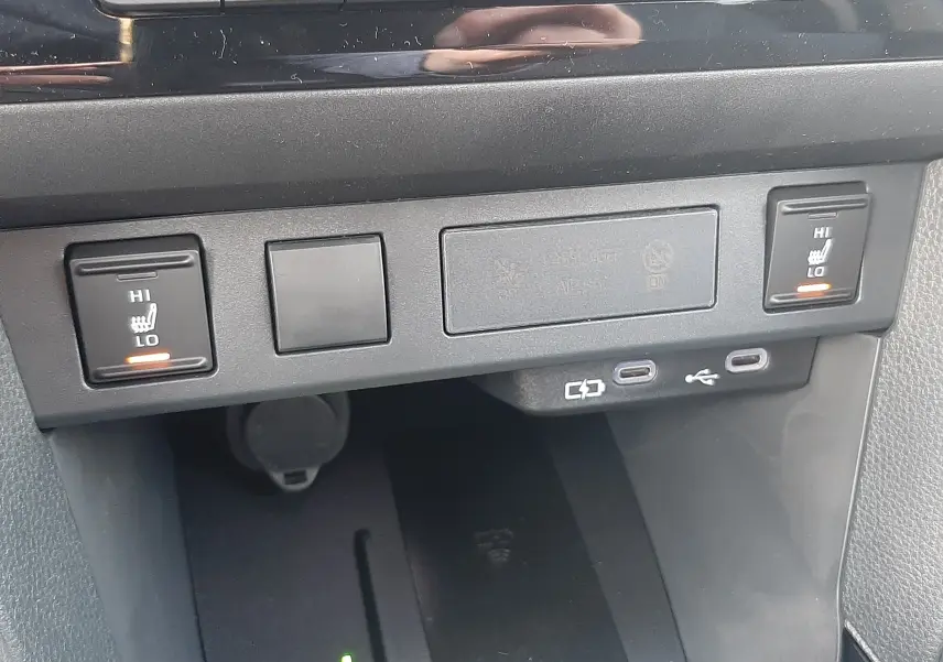 Vue rapprochée de la console centrale de la Toyota Yaris Cross 130H Design 2025, avec commandes de sièges chauffants et ports USB.