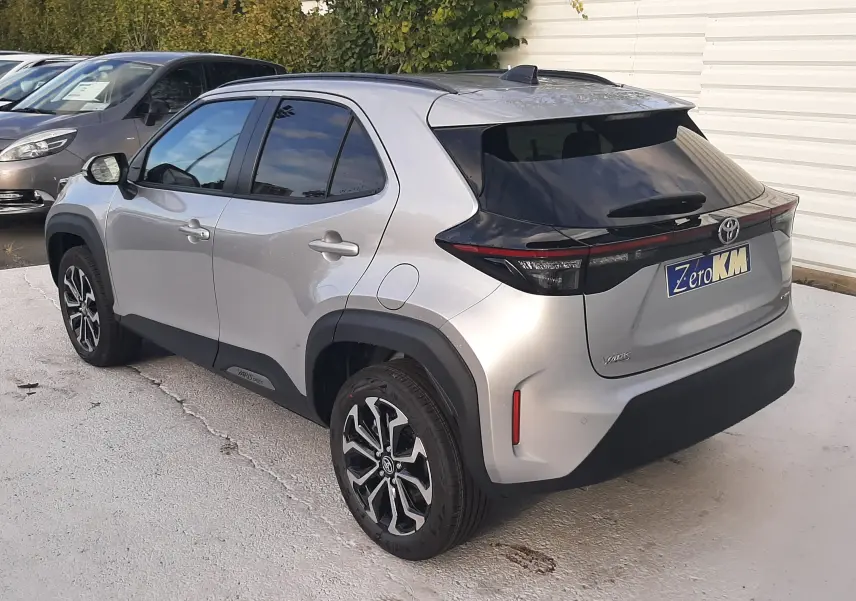 Vue 3/4 arrière droite d'une Toyota Yaris Cross 130H Design gris minéral avec jantes alliage bicolores et vitres teintées.