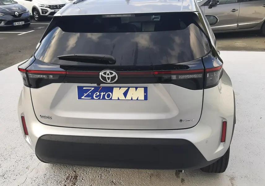 Vue arrière d'une Toyota Yaris Cross 130H Design gris minéral avec feux reliés par une bande noire et logo Toyota visible.