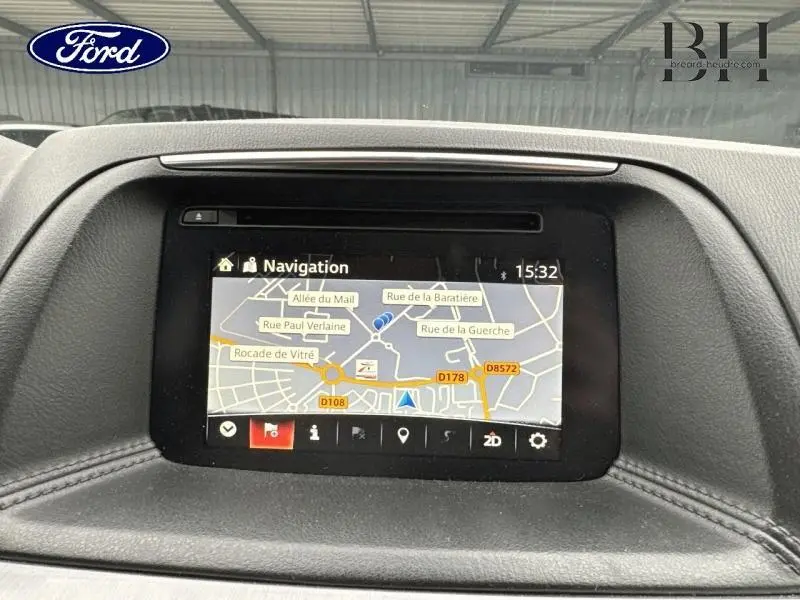 Écran de navigation intégré au tableau de bord d'un Mazda CX-5 2016, affichant une carte routière détaillée.