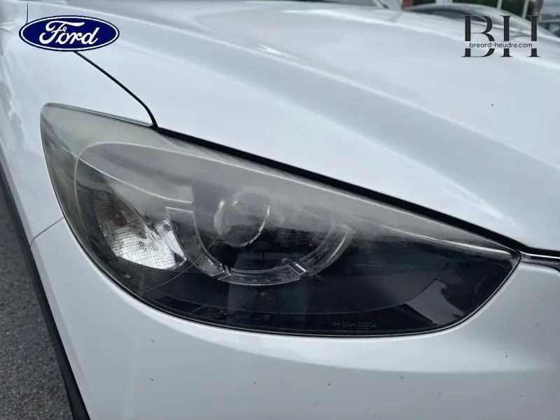 Gros plan sur le phare avant gauche du Mazda CX-5 2016 en blanc nacré Snowflake White Pearl Mica.