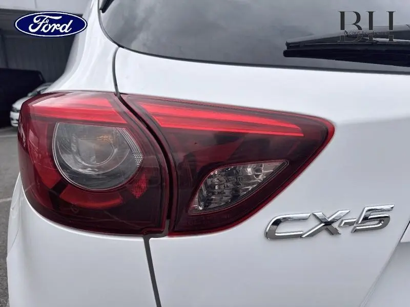 Gros plan sur le feu arrière gauche d'un Mazda CX-5 blanc nacré avec le logo CX-5 visible sur le hayon.