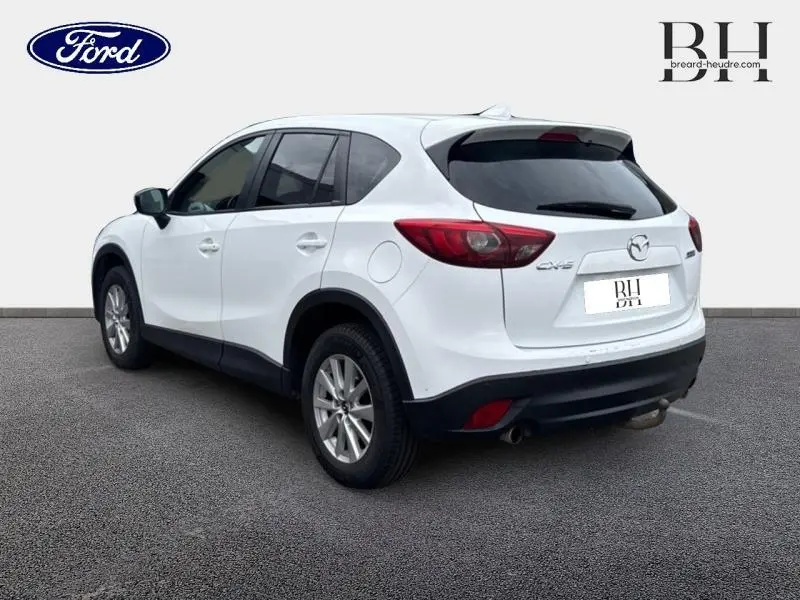 Vue 3/4 arrière droite d'un Mazda CX-5 blanc perle avec feux arrière rouges et jantes alliage.