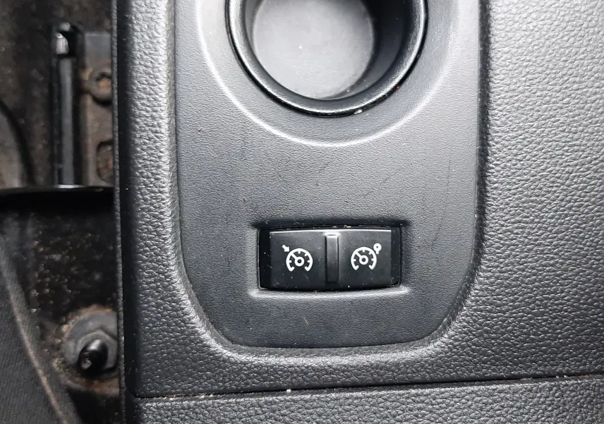 Gros plan sur les boutons de régulateur et limiteur de vitesse noirs dans l’habitacle du Dacia Duster gris Cassiopée.