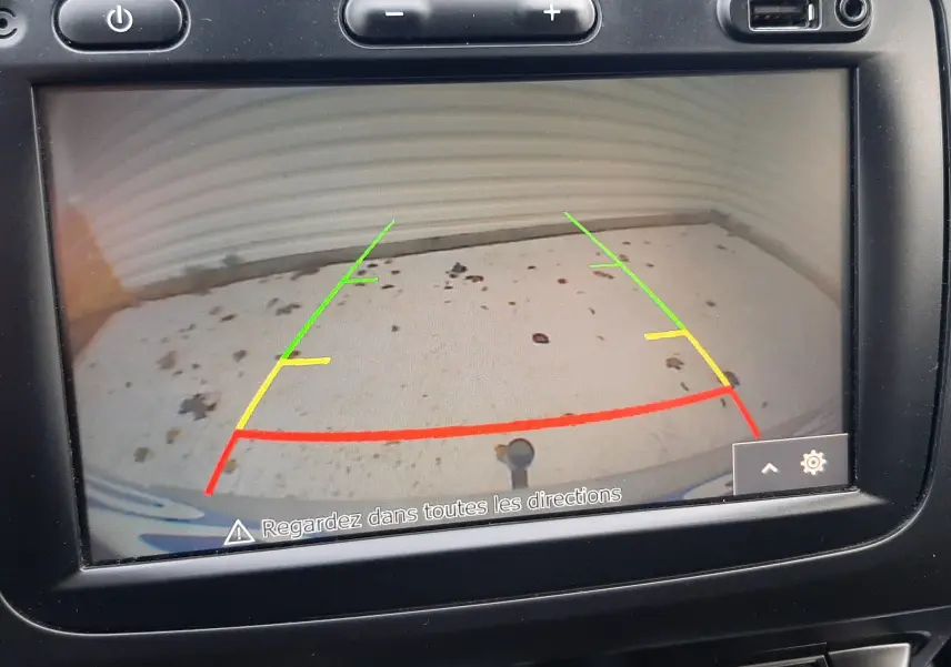 Écran de caméra de recul du Dacia Duster 2019 montrant le sol avec lignes de guidage colorées dans l'habitacle noir.