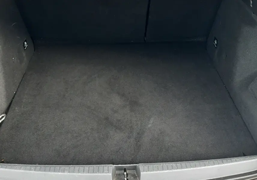 Coffre ouvert du Dacia Duster gris Cassiopée, vue plongeante sur l’espace de rangement vide et propre.