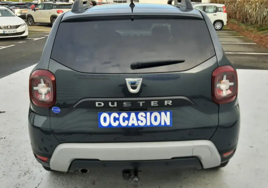 Vue arrière d'un Dacia Duster gris Cassiopée avec plaque "OCCASION" et feux arrière au design carré.